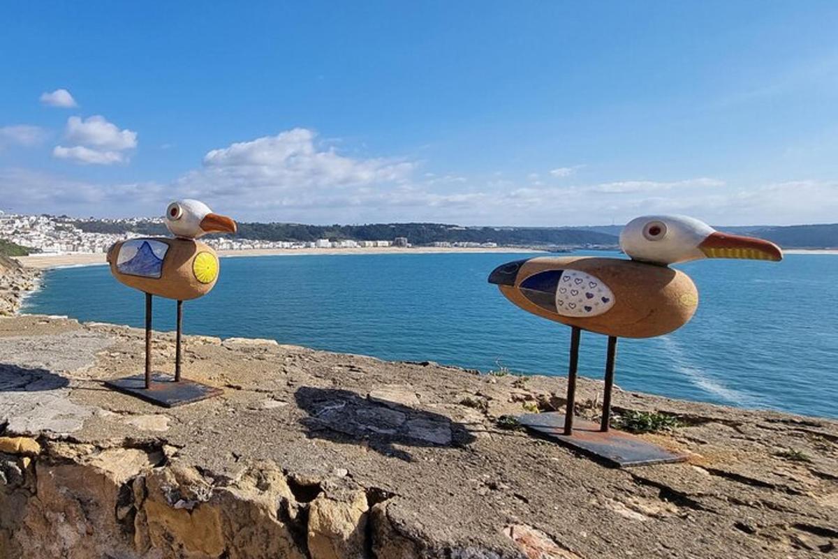 dois pássaros de plástico sentados em uma rocha perto da água
