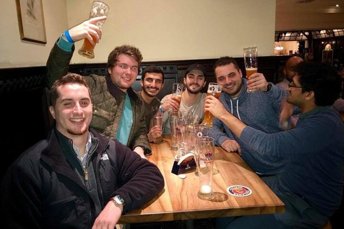 skupina mužů sedících kolem stolu a popíjejících pivo