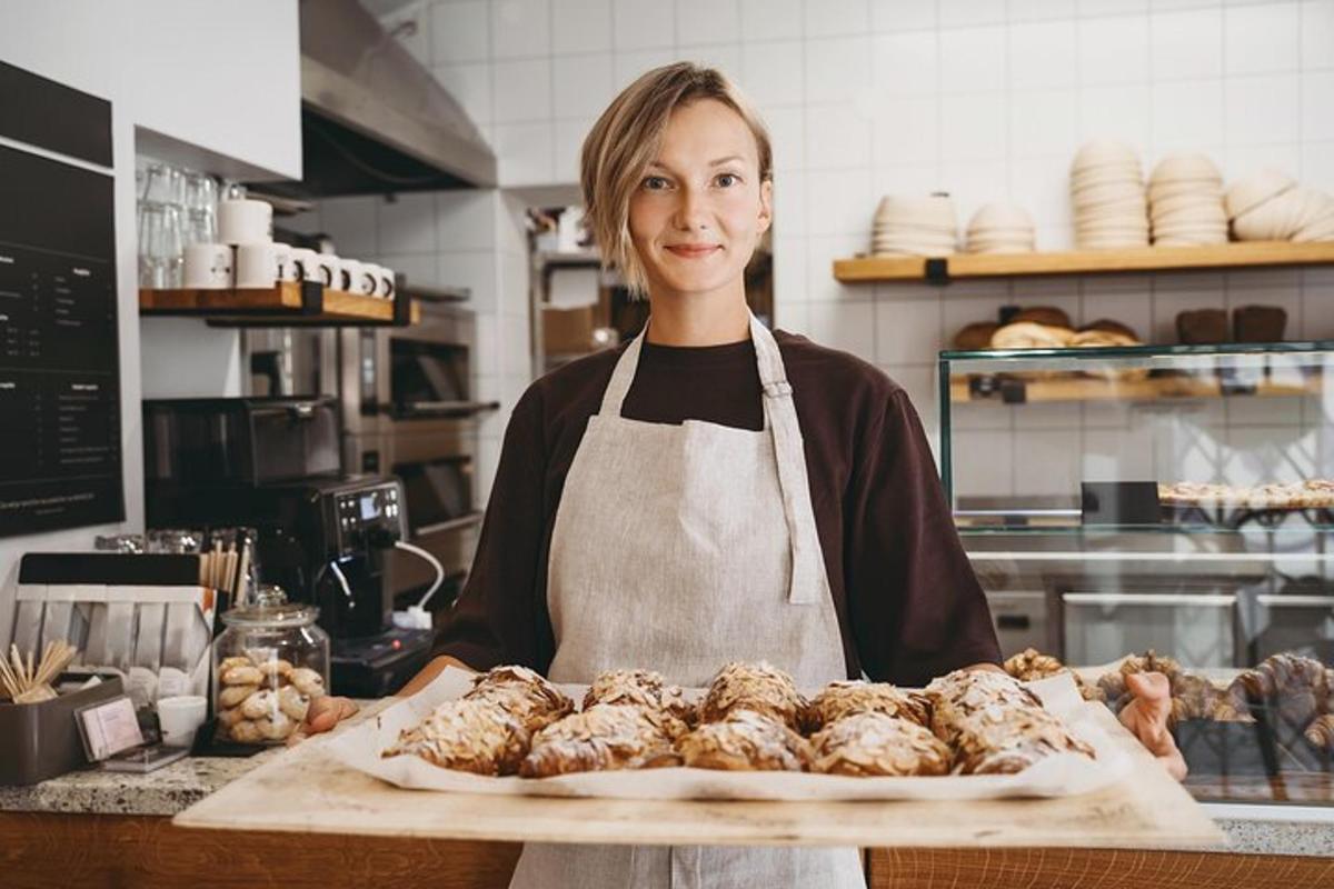 o femeie în bucătărie ținând o tavă cu produse de patiserie