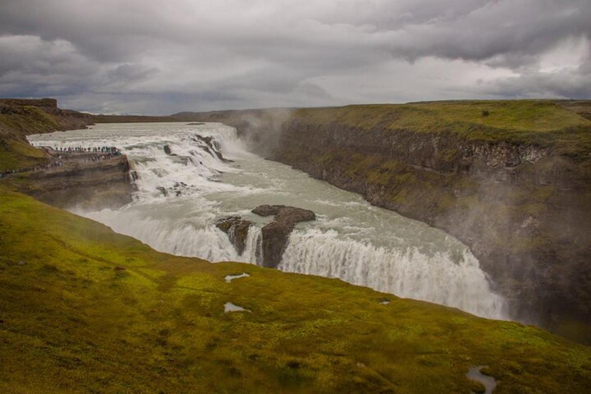 a waterfall on the side of a mountain with grass