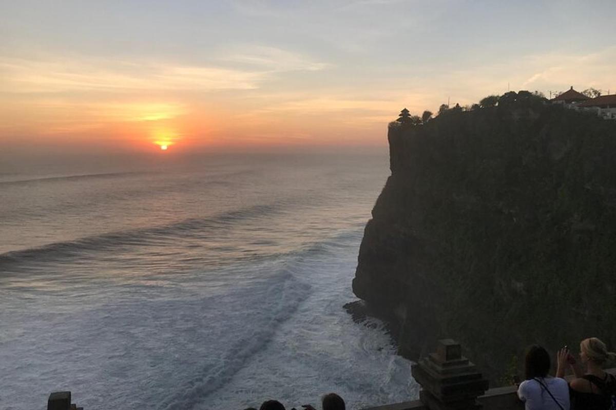um grupo de pessoas assistindo ao pôr do sol sobre o oceano