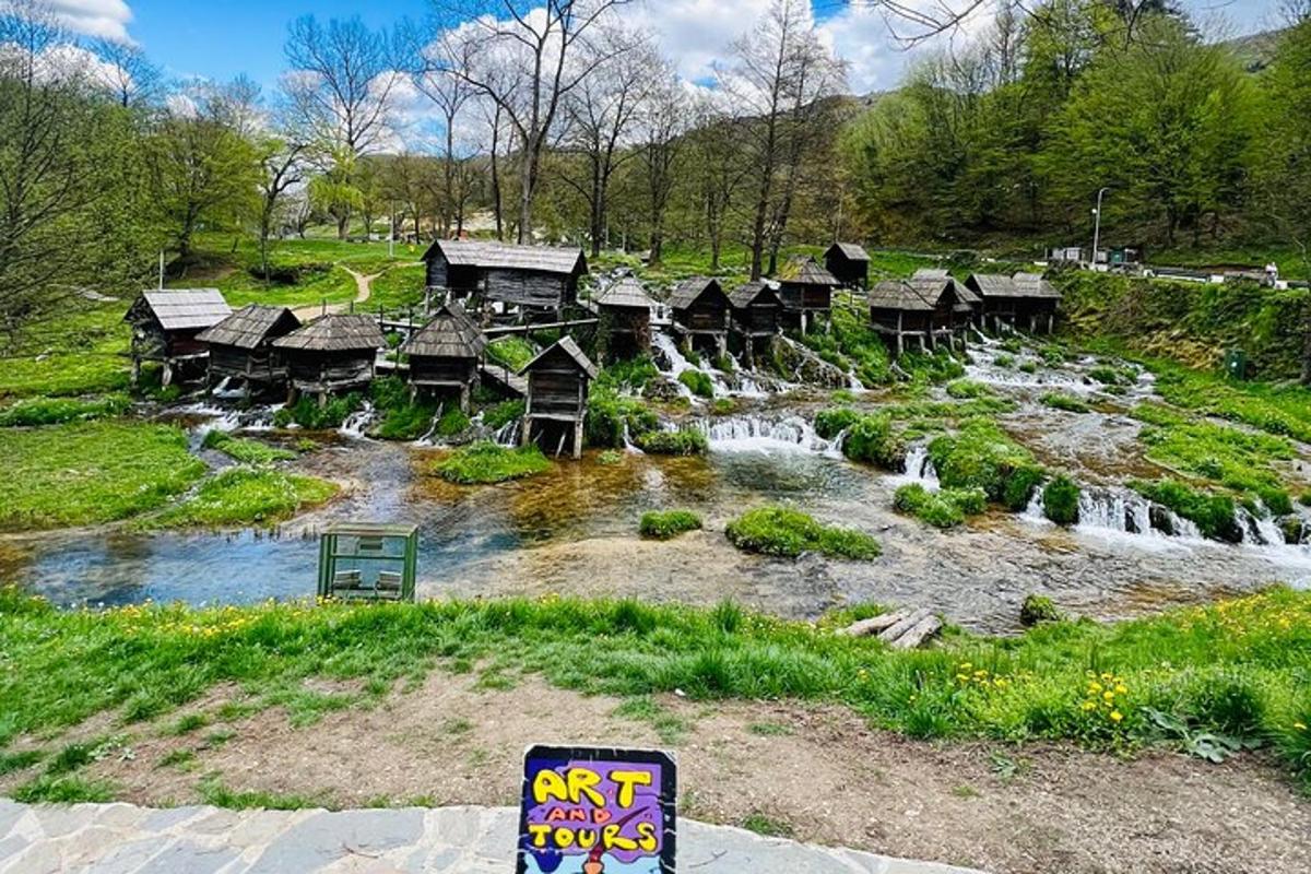 a group of wooden huts and a waterfall