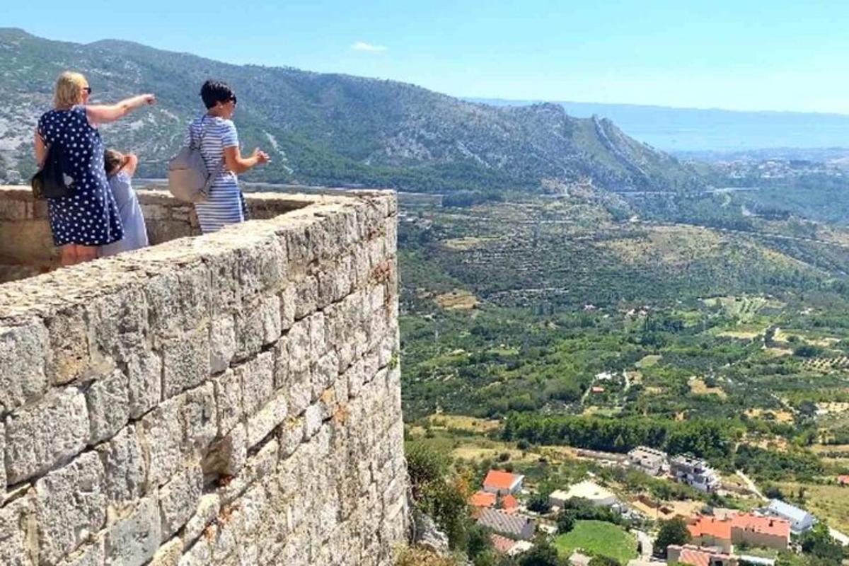 Δύο γυναίκες στέκονται πάνω σε έναν πέτρινο τοίχο κοιτάζοντας μια κοιλάδα