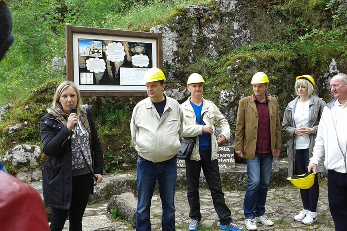 skupina ljudi s čeladami, ki stojijo pred znakom