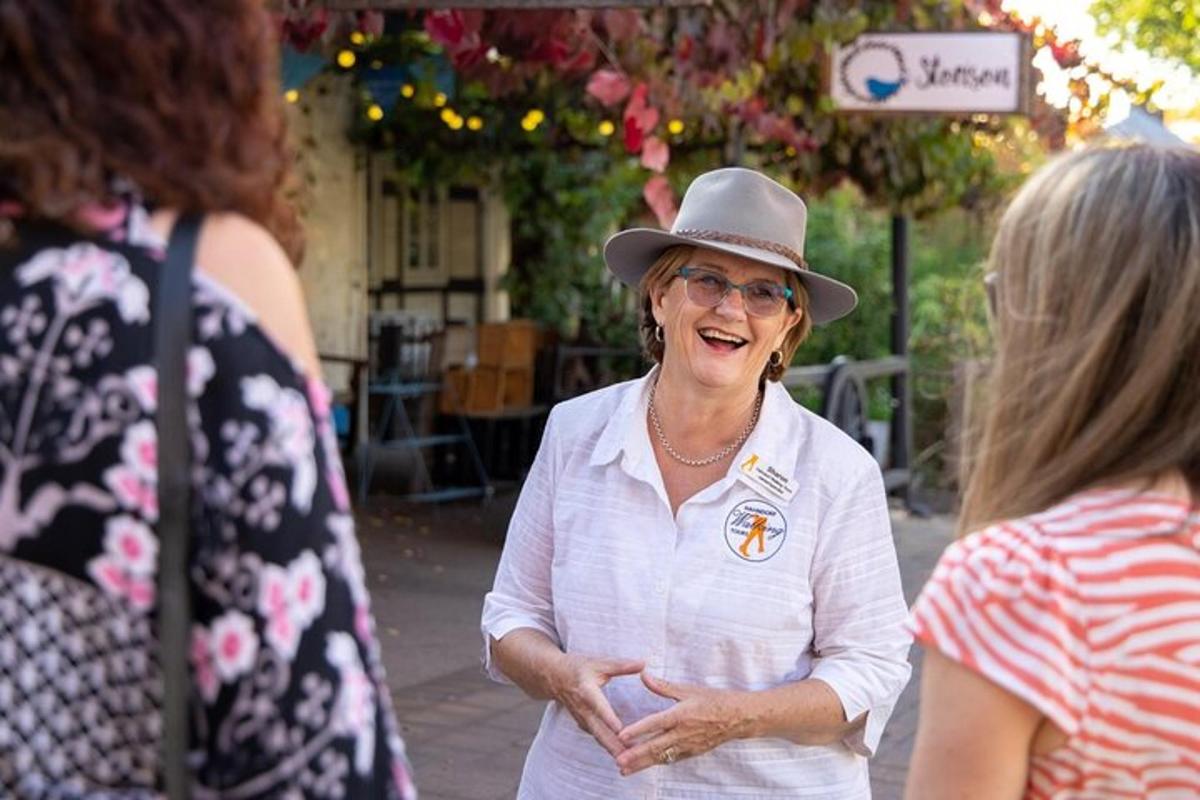 an older woman wearing a hat talking to another woman