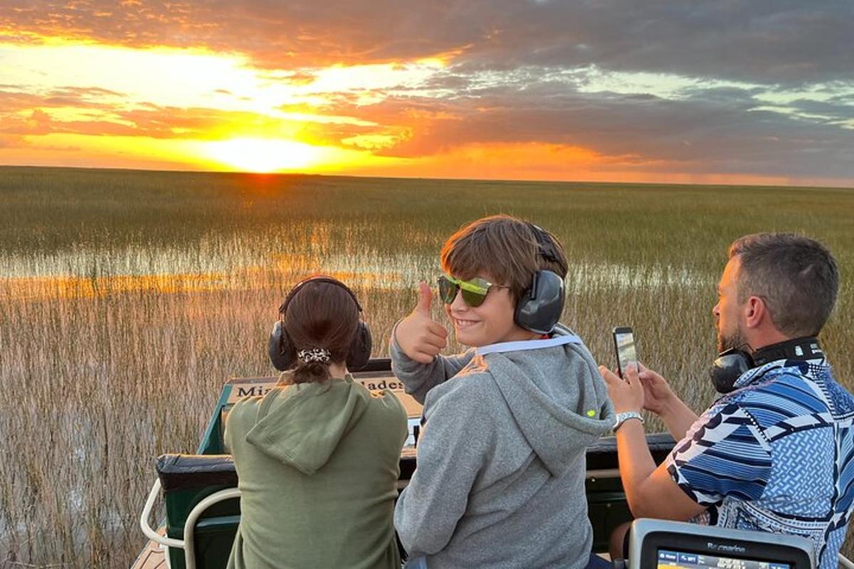 a group of people sitting on a boat watching the sunset