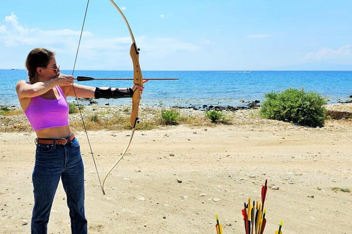a woman holding a bow and arrow on the beach