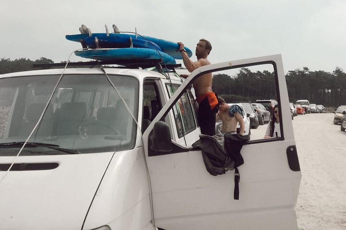 Dos hombres están de pie en el techo de una camioneta blanca.