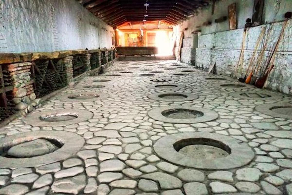 Una habitación vacía con suelo de piedra con desagües circulares.