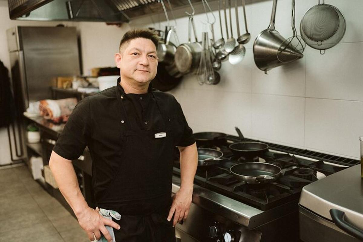 Un hombre en una cocina de pie frente a una estufa.