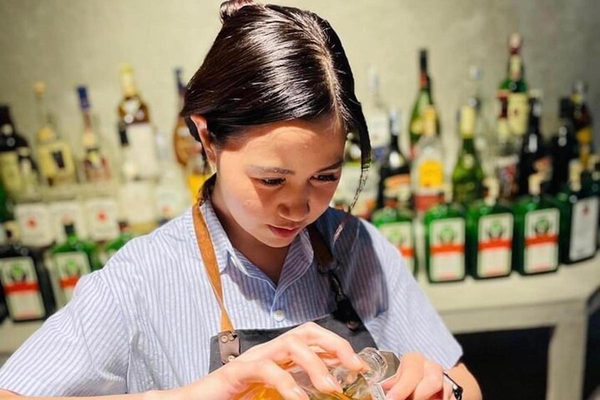 một người phụ nữ đang đứng ở quầy bar pha chế đồ uống