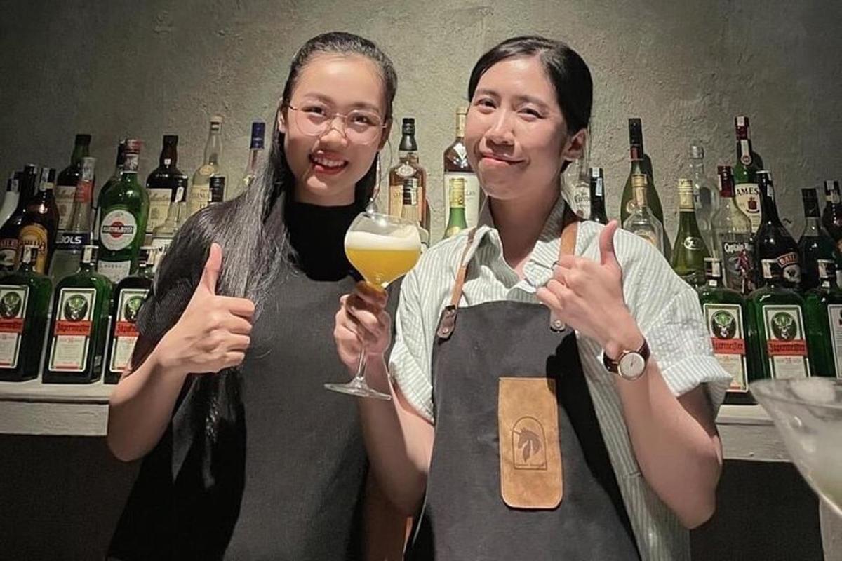 two women standing in a bar with a glass of wine