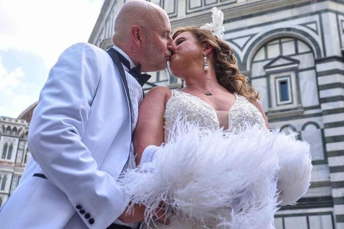 Una novia y un novio besándose frente a un edificio