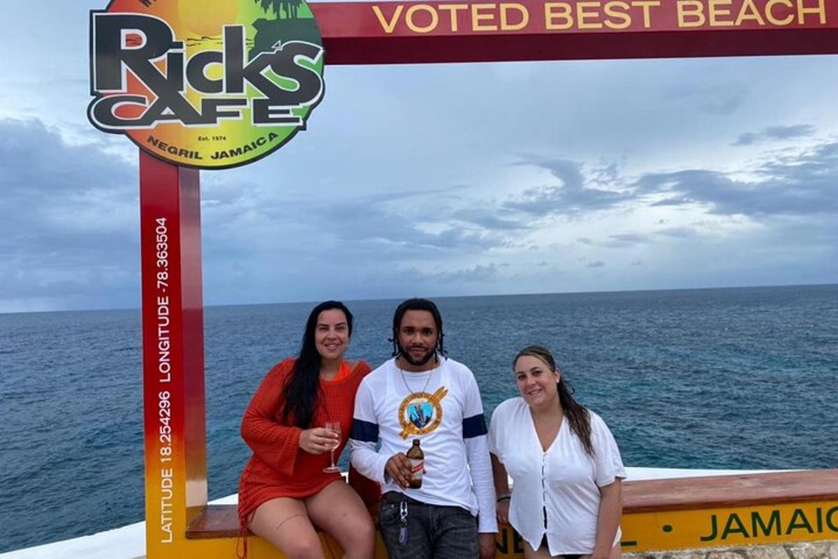 tre persone posano per una foto di fronte all'oceano