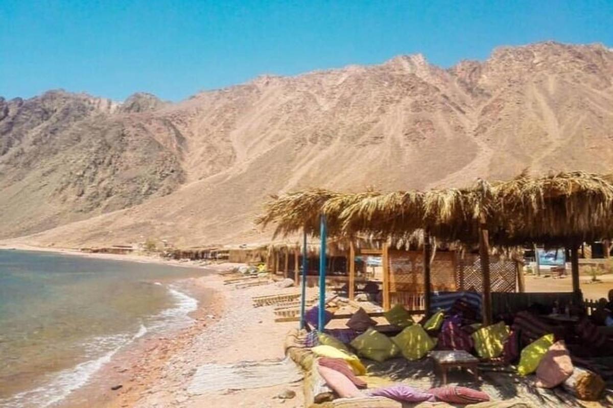 een strand met een strooien parasol en stoelen en de oceaan