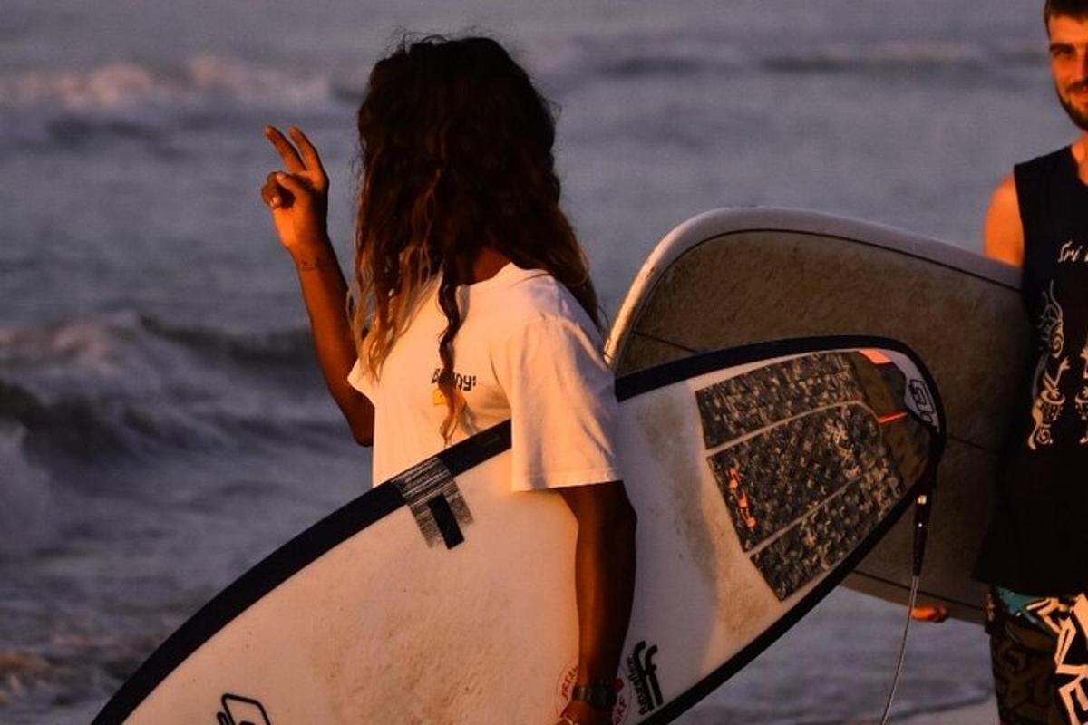 a woman standing on the beach holding a surfboard