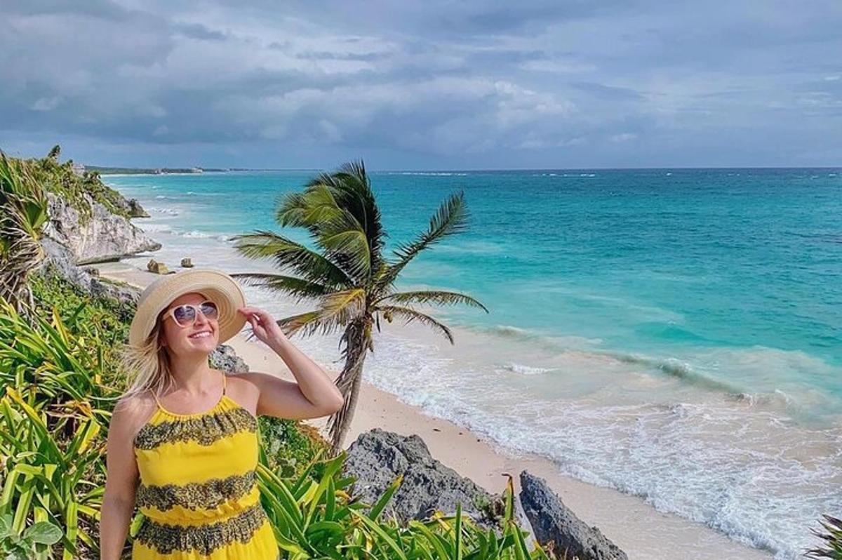 una donna in piedi accanto a una spiaggia con una palma