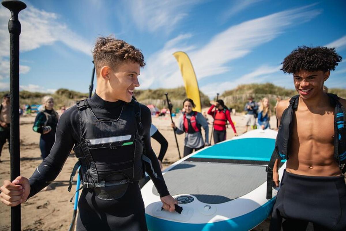 a man in a wetsuit holding a surfboard on the beach