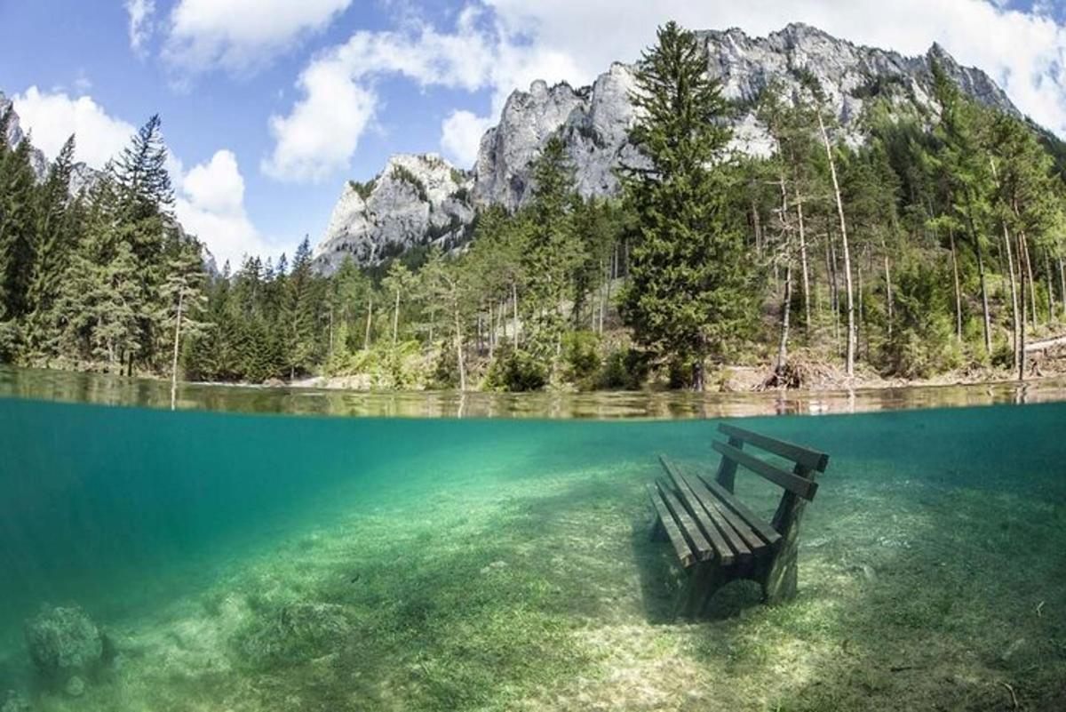 o bancă așezată în apă în fața unui munte