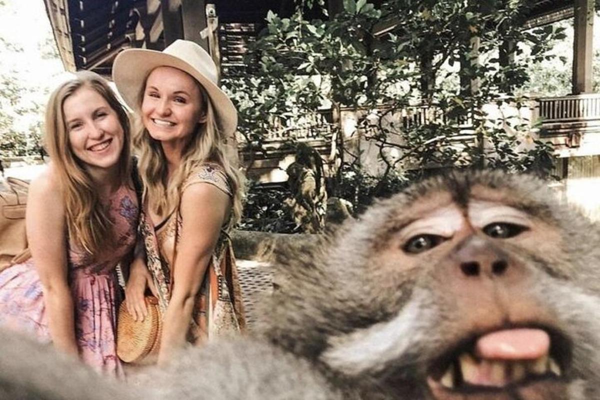 divas sievietes sēž blakus pērtiķim priekšā
