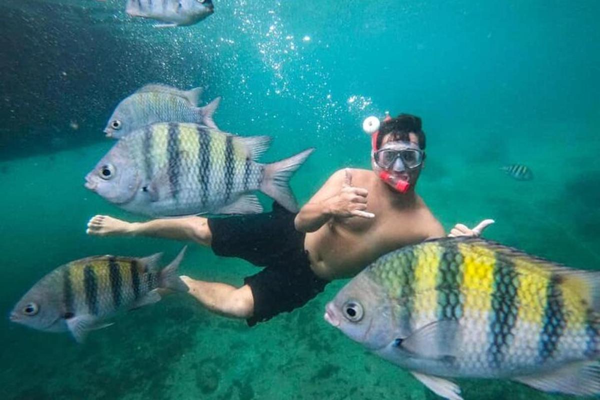 un uomo in acqua con un pesce in bocca