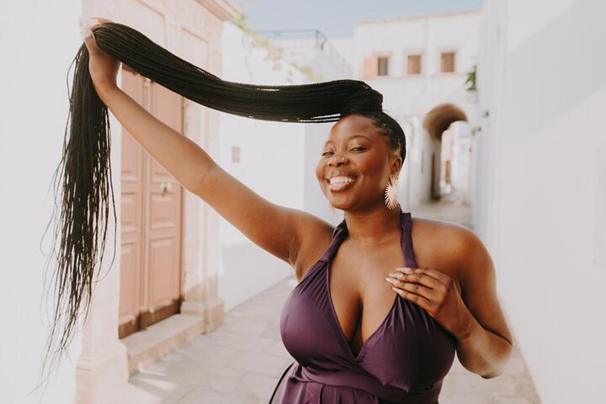 uma mulher de vestido roxo segurando o cabelo