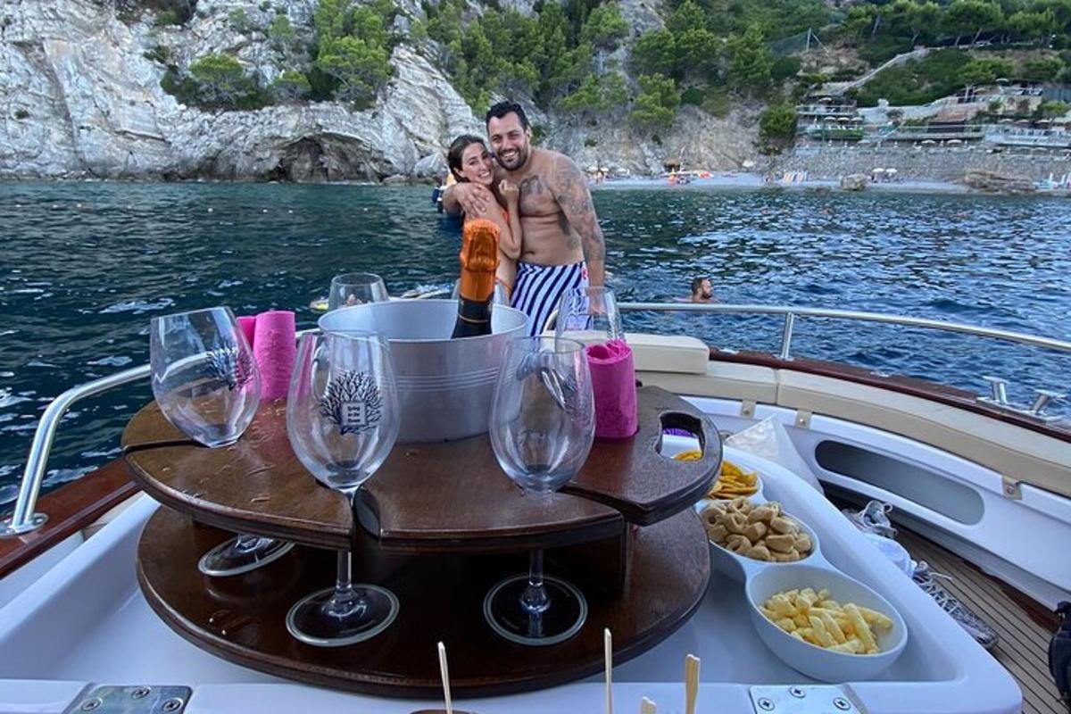 un home i una dona drets en un vaixell amb una taula amb copes de vi