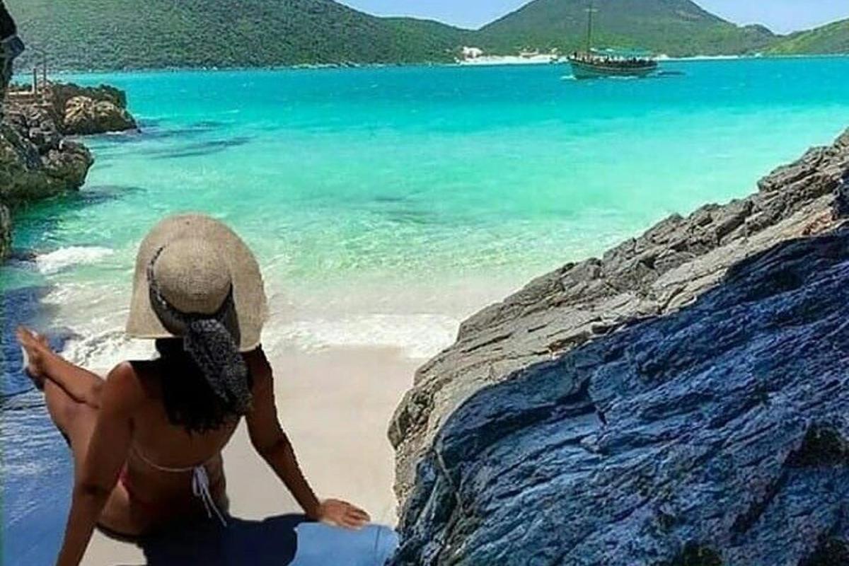 una donna con un cappello seduta su una spiaggia