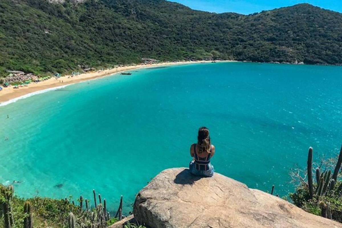 una donna seduta su una roccia che domina una spiaggia