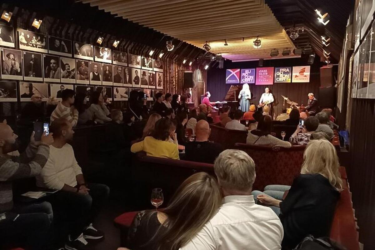 o mulțime de oameni așezați într-un teatru care privesc un bărbat pe scenă