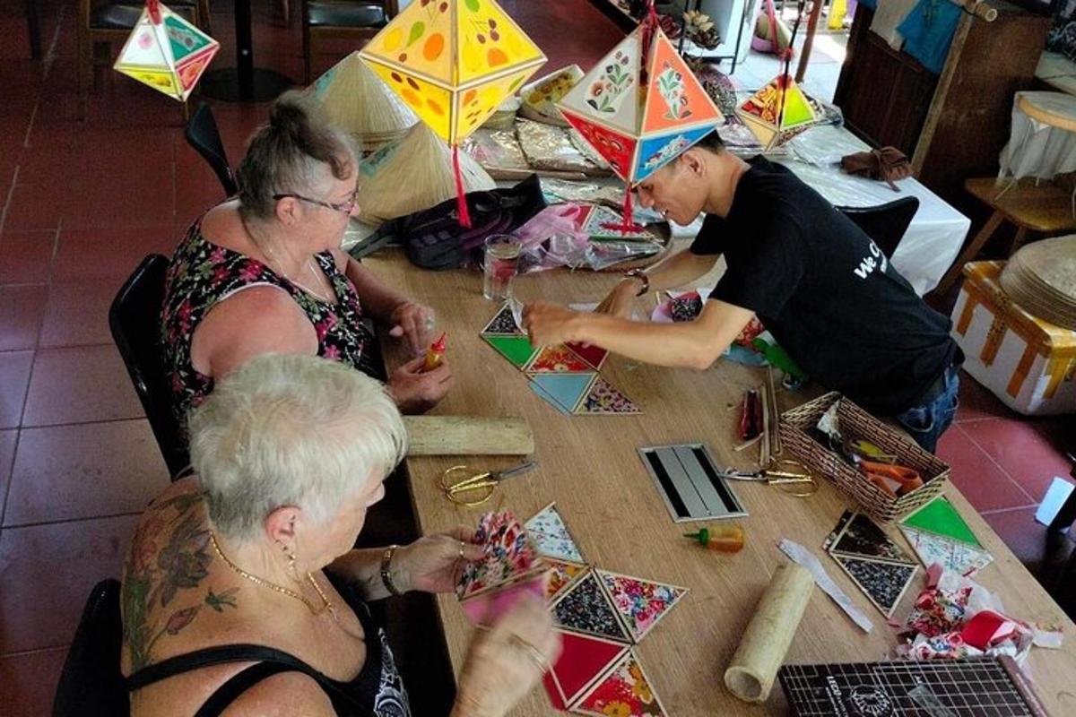 a group of people sitting at a table making kites