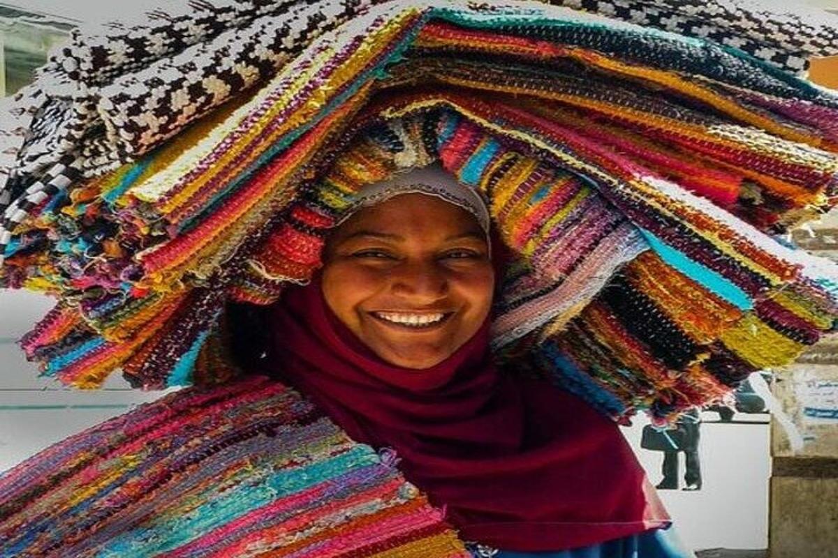 une femme porte une pile de couvertures sur sa tête