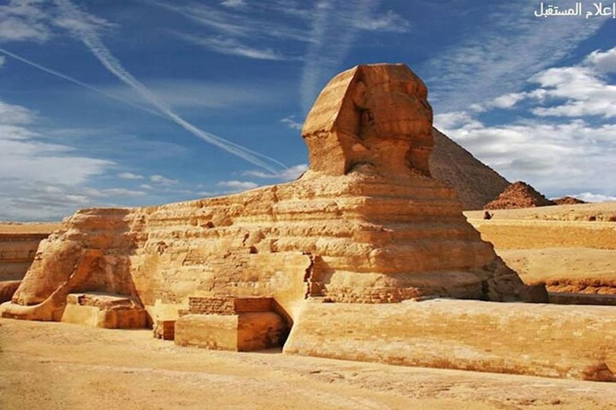 Anubisův pomník v poušti s pyramidou v pozadí