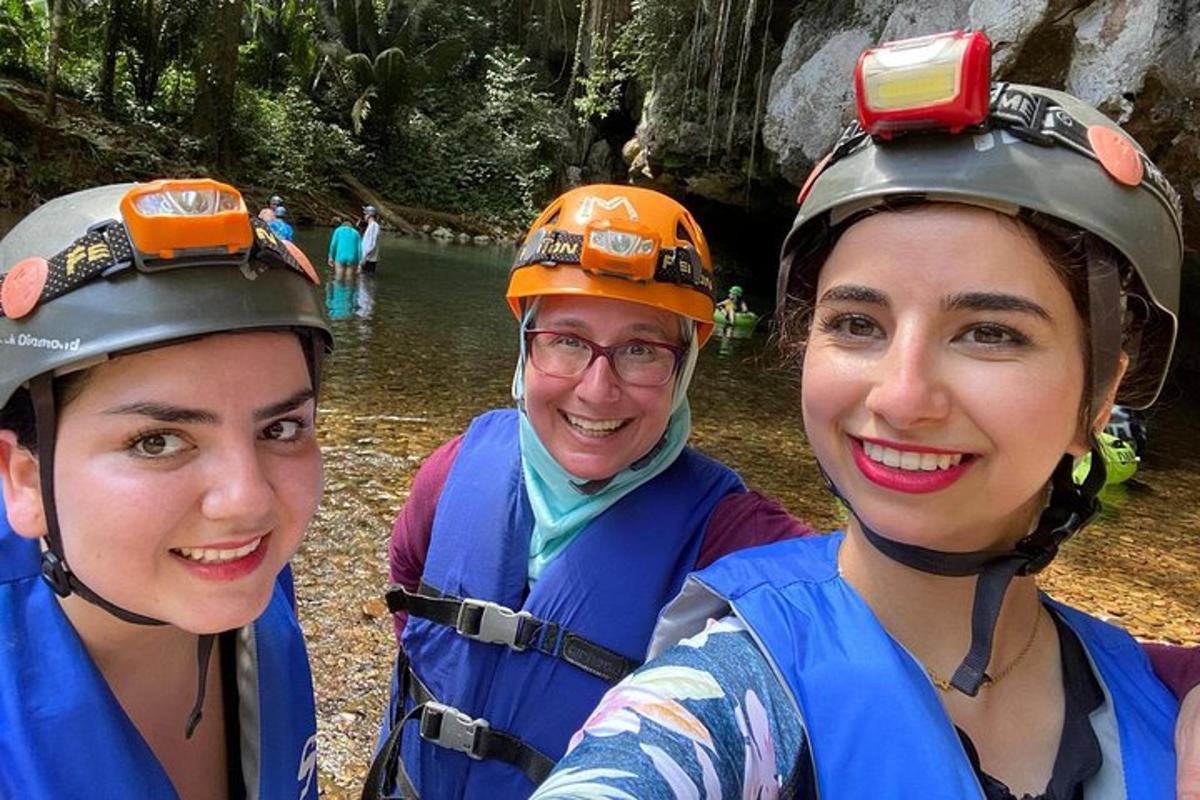three people wearing life jackets and helmets standing in a river