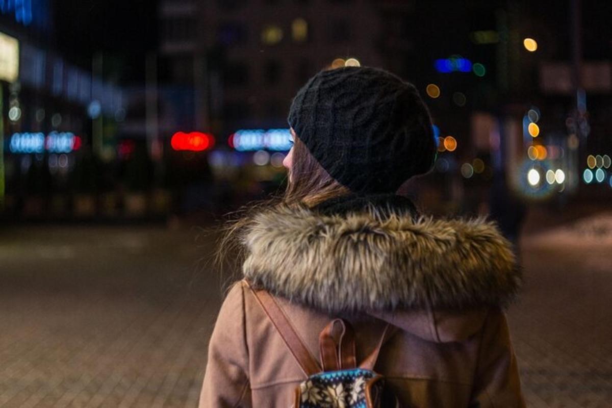 kona gengur niður götuna að nóttu til í loðkápu