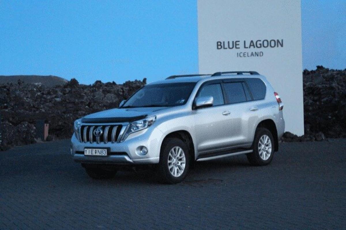 a silver jeep parked in front of a sign