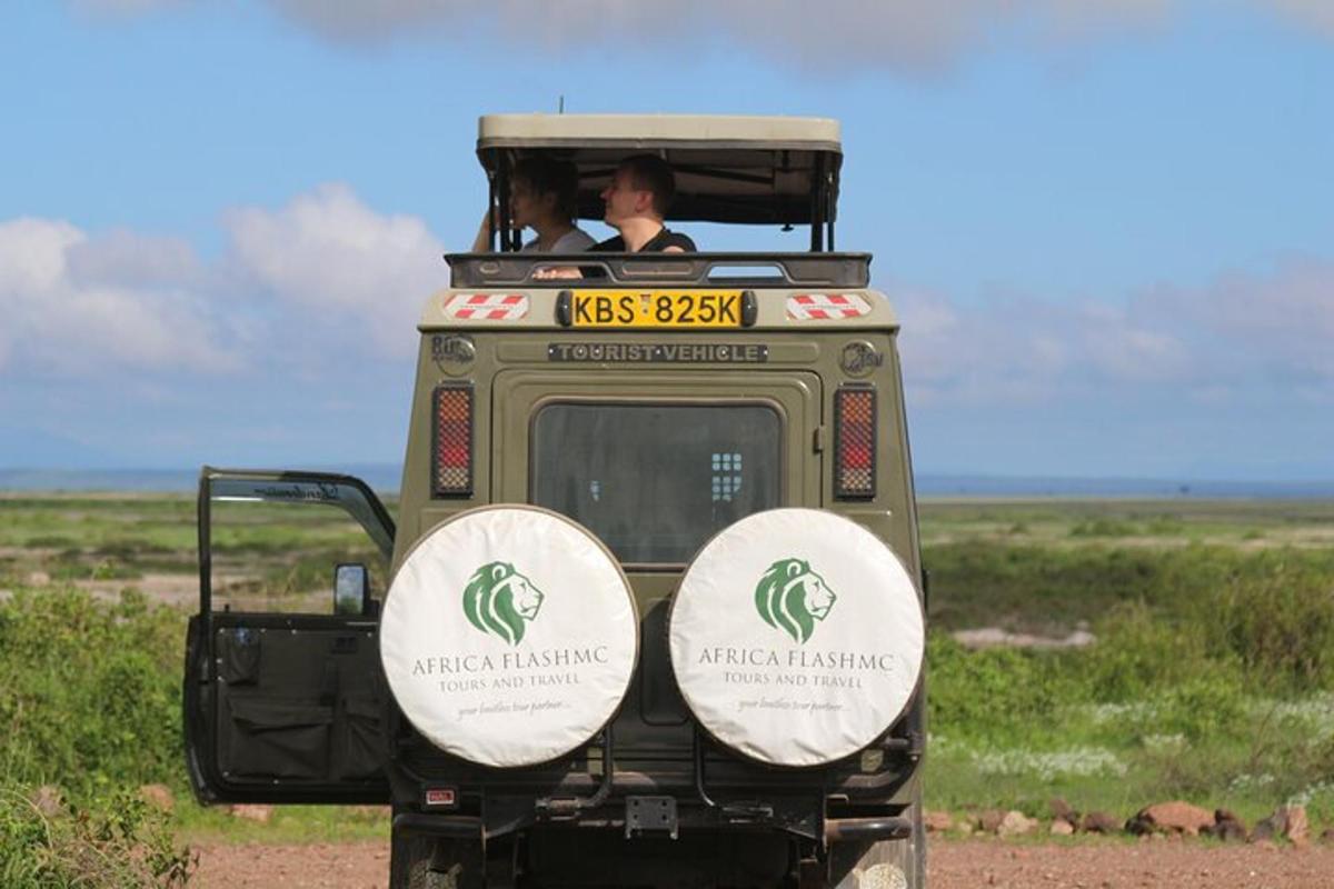 a green safari vehicle with two people in the back