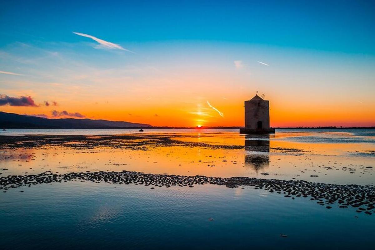 un far a la platja amb la posta de sol al fons