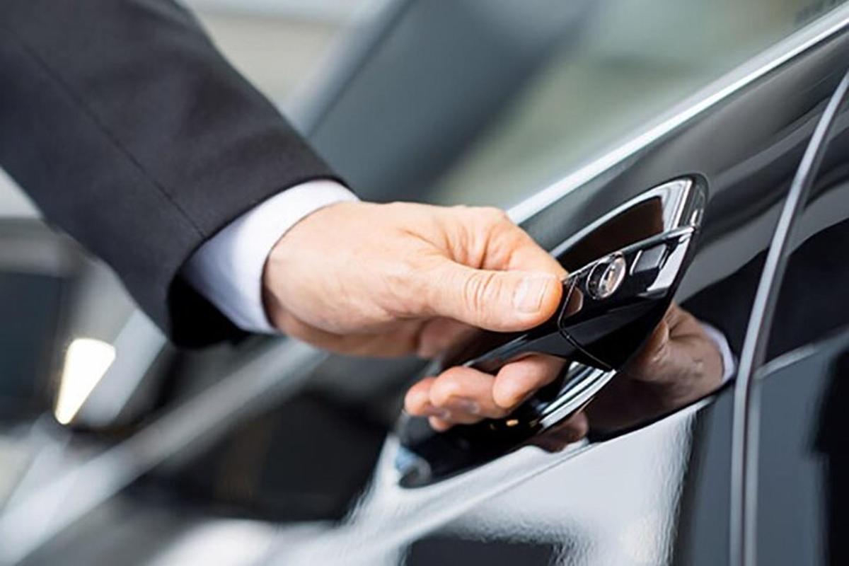 muž v obleku držící mobilní telefon u auta