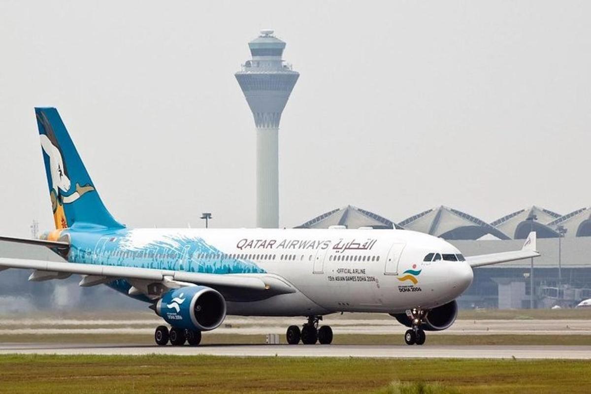 an airplane on a runway with a control tower in the background