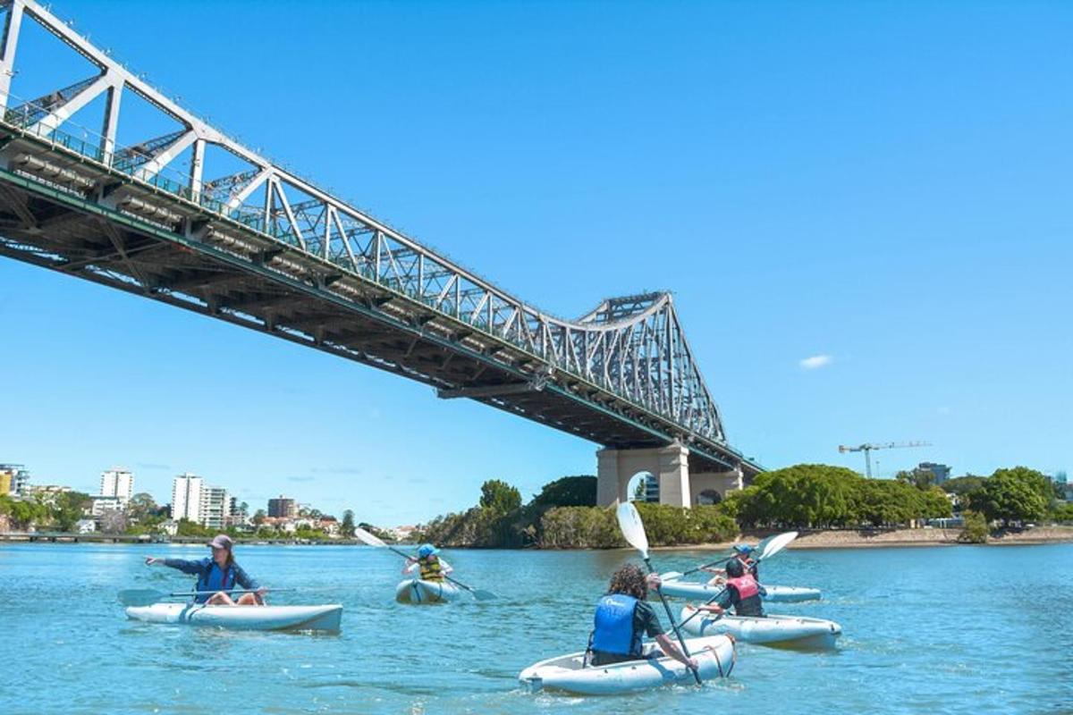 a group of people kayaking in the water under a bridge