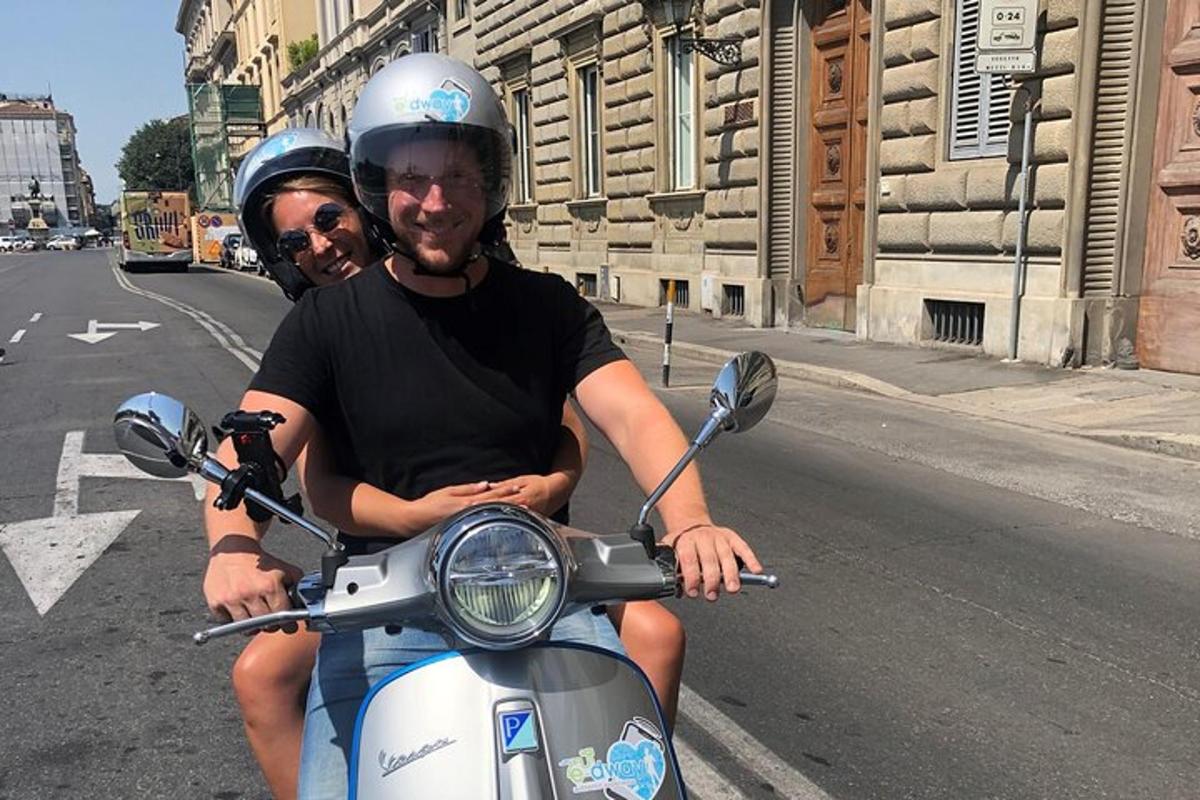 two men riding on a scooter on the street