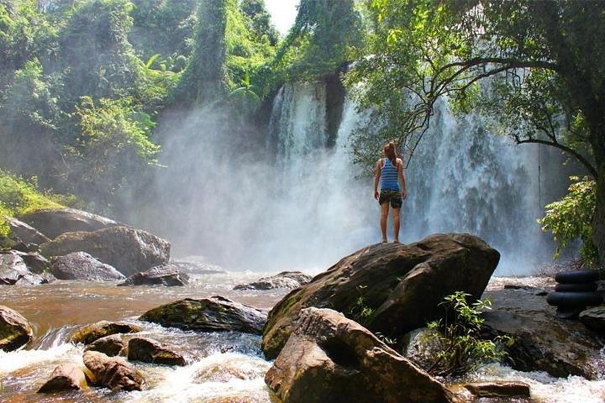 seseorang yang berdiri di atas batu di hadapan air terjun