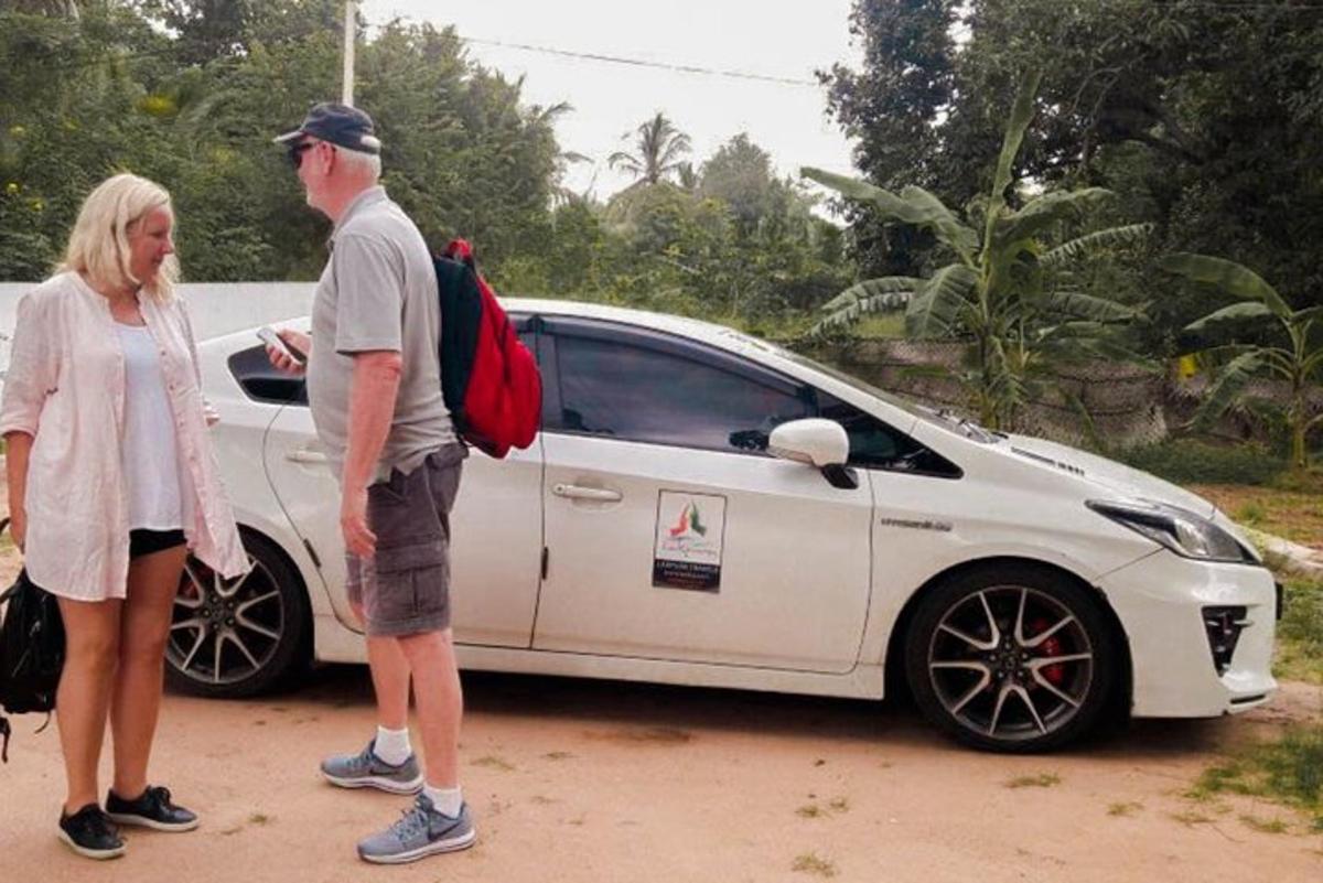 moški in ženska stojita poleg belega avtomobila