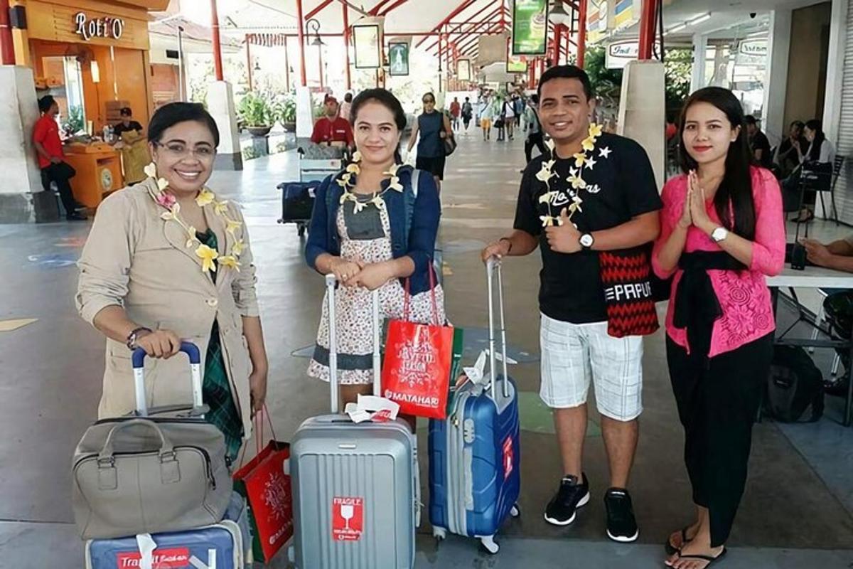 sekelompok orang berdiri di bandara dengan barang bawaan