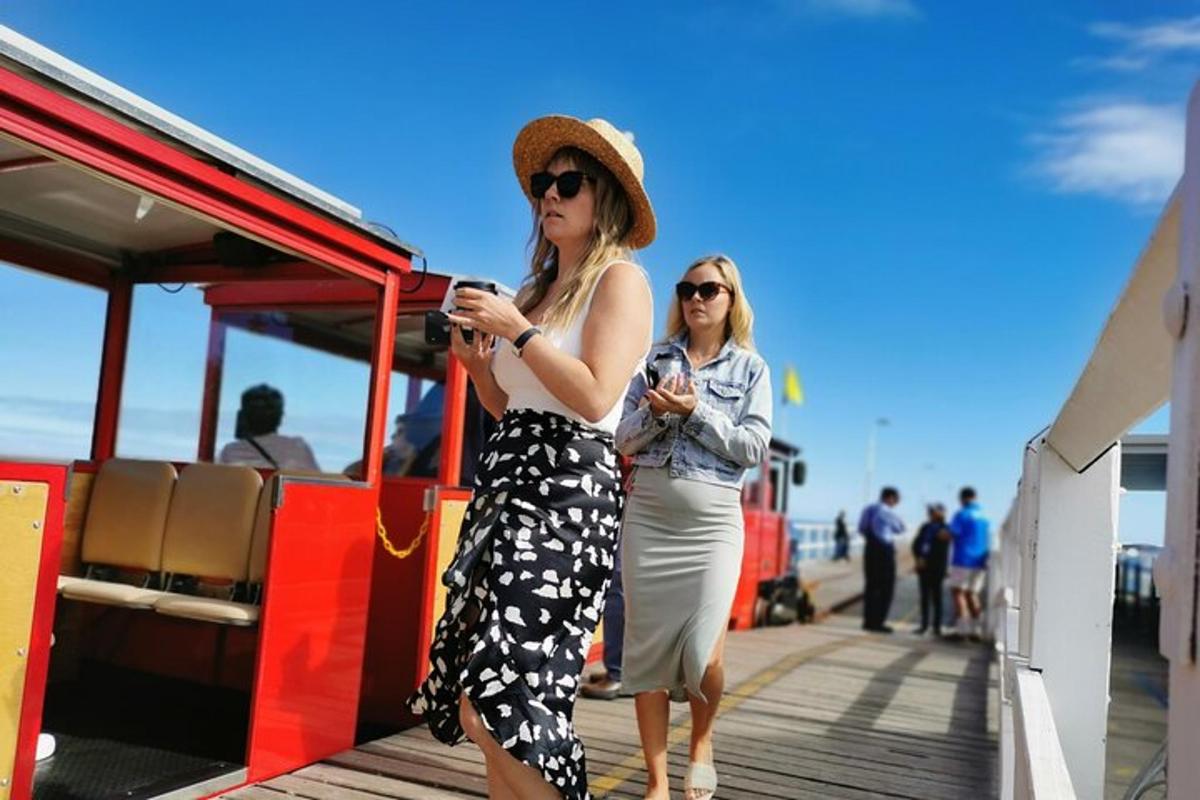 dvě ženy stojící na molu a dívající se do svých mobilních telefonů