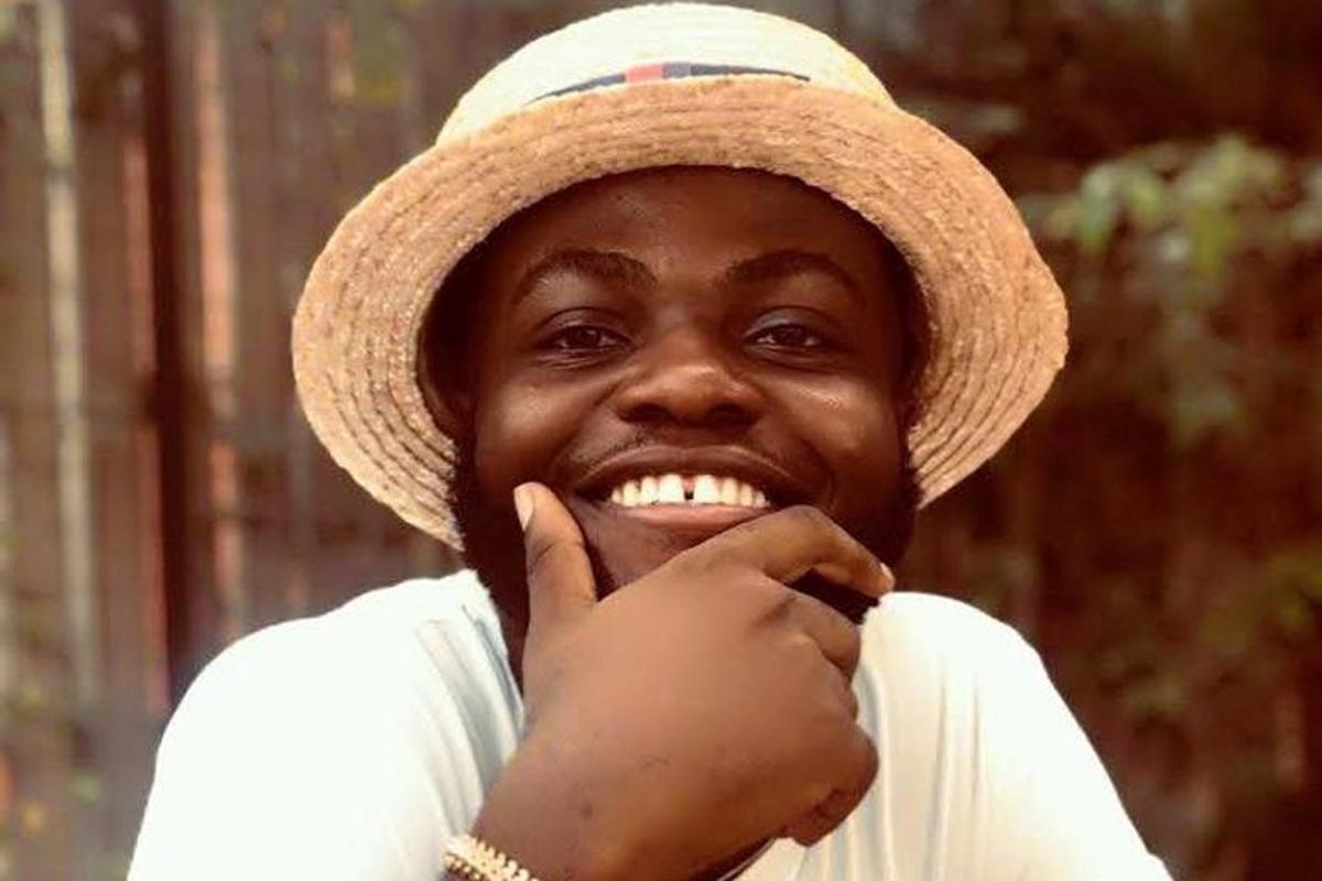 a man wearing a hat with his hand in his mouth