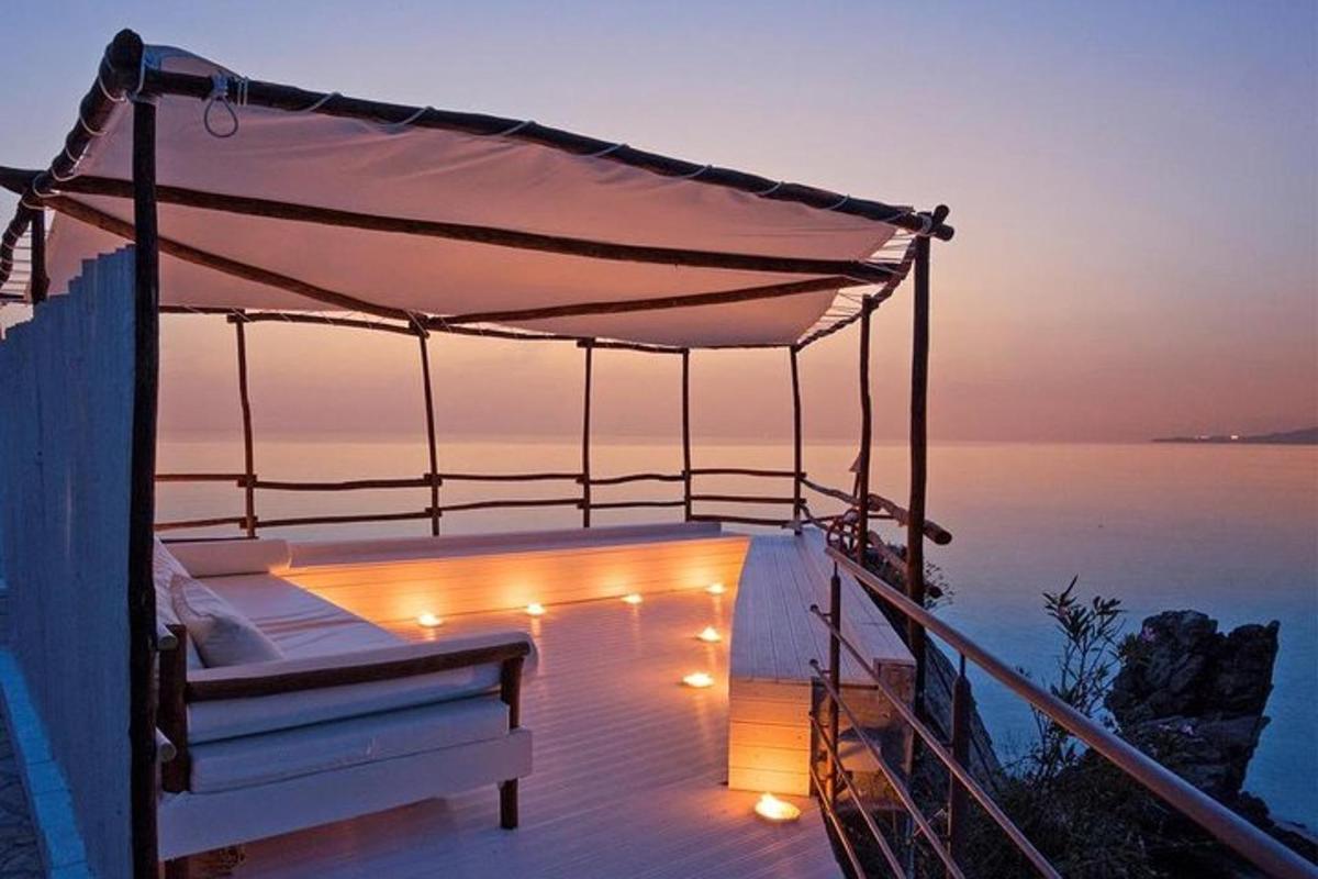 a bed on a deck with lights on the water