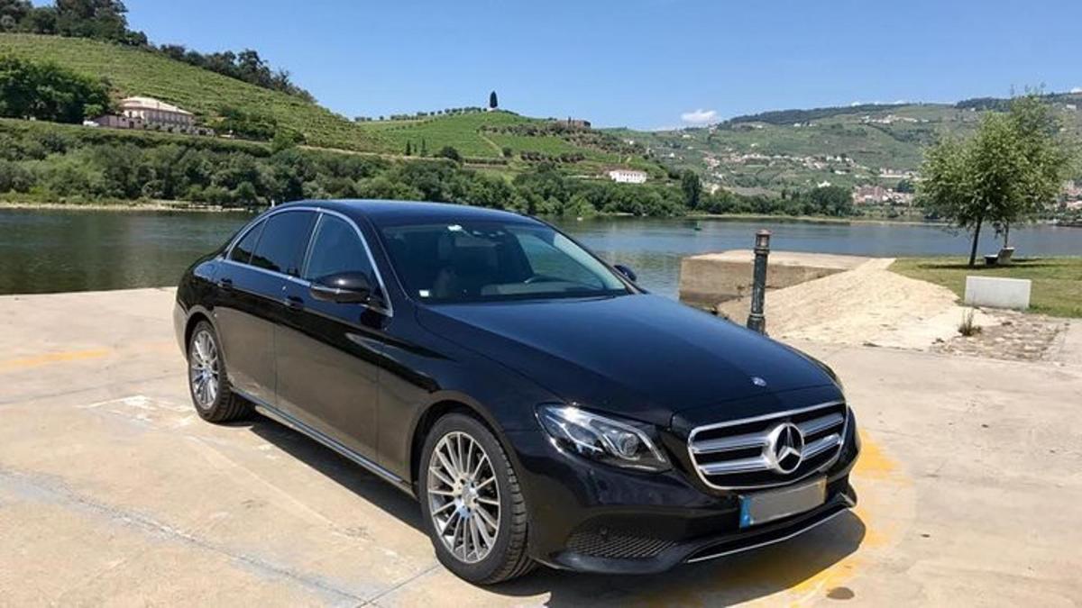 Un coche negro estacionado en un estacionamiento junto a un río.
