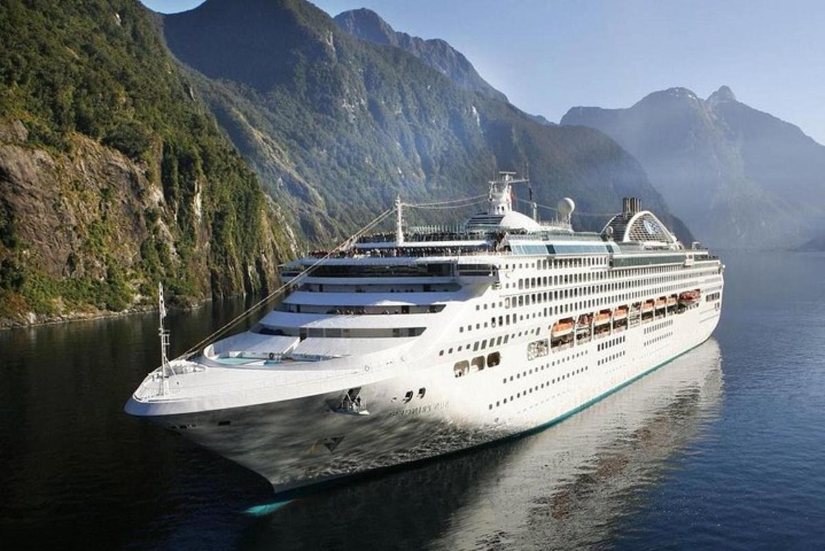 um navio de cruzeiro na água perto das montanhas